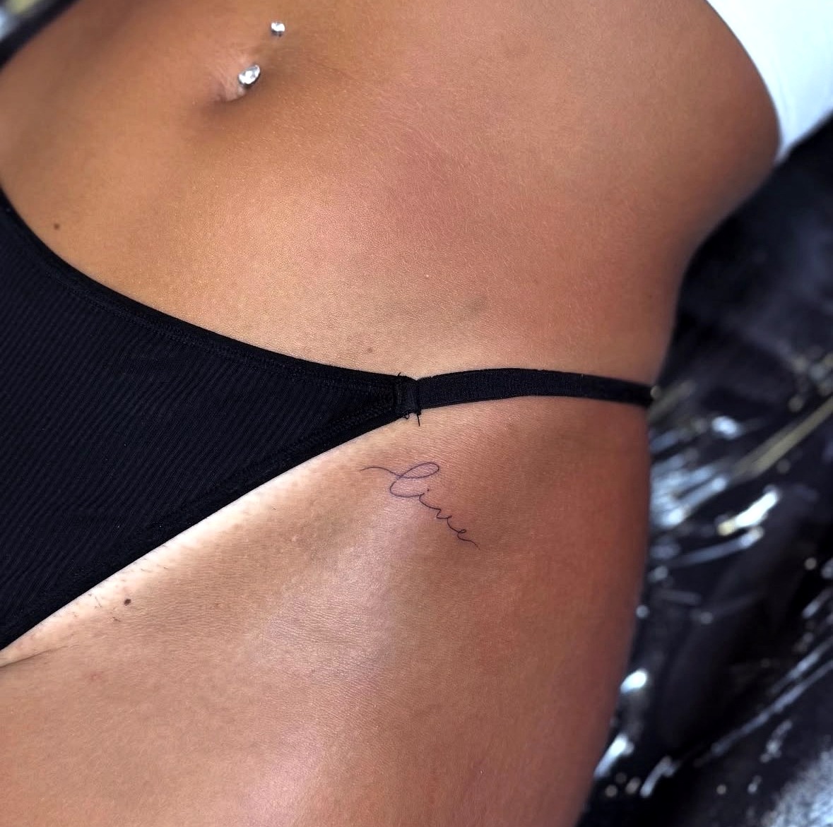 Fine line 'live' script tattoo on the hip