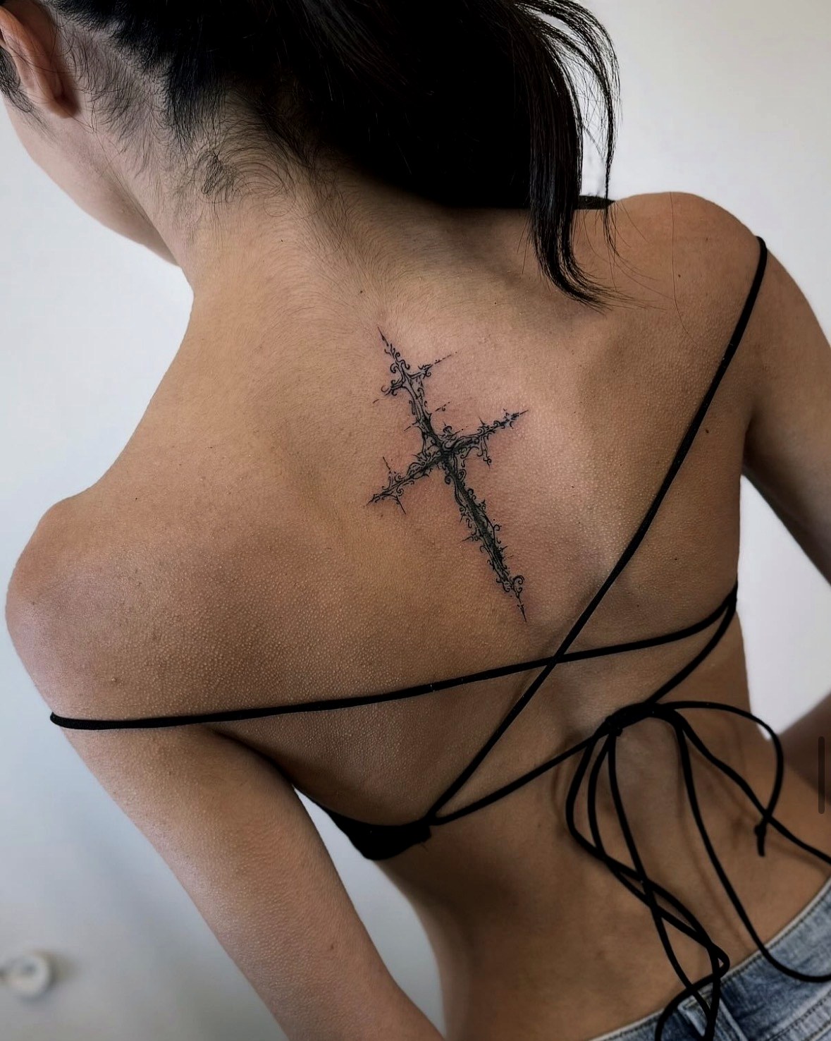 Ornate cross tattoo on upper back